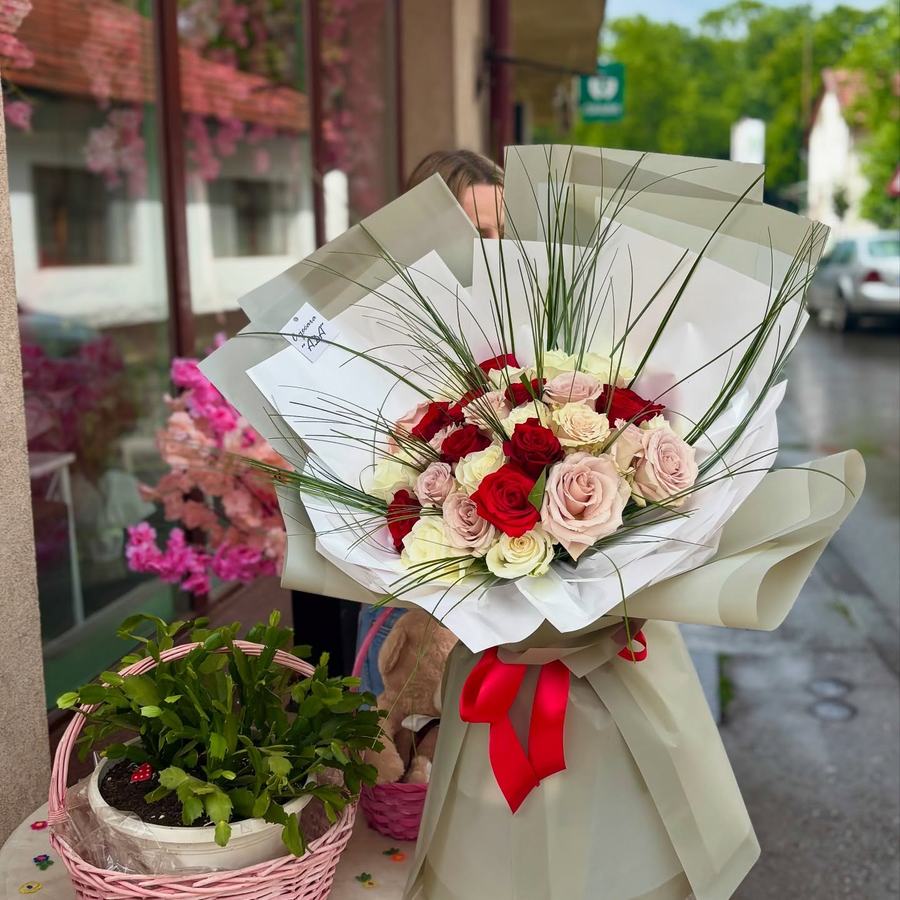 Buket crvenih i puderasto roze ruža s crvenom vrpcom